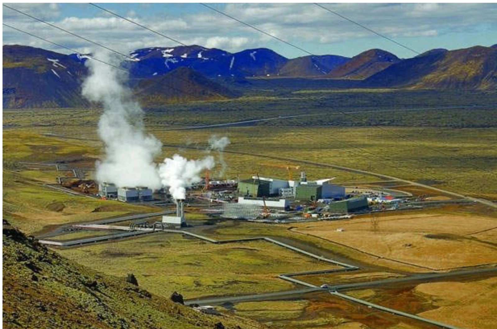 Geothermal power plant with steam rising in a volcanic valley