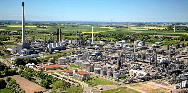 Industrial plant surrounded by wind turbines and farmland